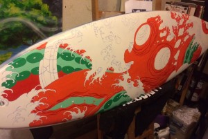 San Diego artist, John Sabin working hard on painting this board donated from Firewire Surfboard