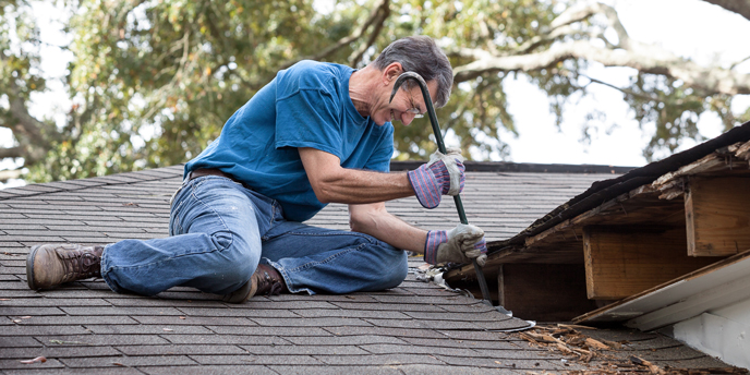 Man With Crowbar Repairing Leaky Roof
