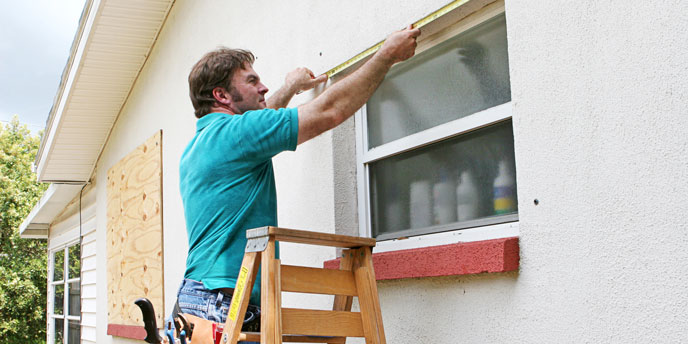 Man Installing Plywood Hurricane Shutters