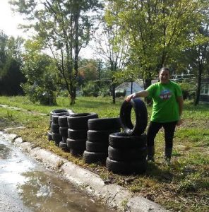 AMUS volunteer posing with collected tires.