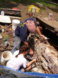 Volunteers engaged in historic preservation of a brick wall.