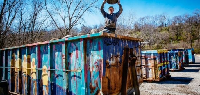 Volunteer standing triumphantly atop a dumpster