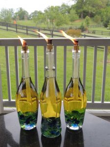 Wine Bottles Turned Into Oil Lamps, With Lit Wicks. 