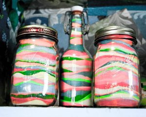 Variety of Bottles and Jars Filled With Layers of Colorful Sand.