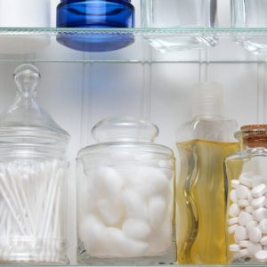 Using Glass Jars Inside a Medicine Cabinet to Hold Cotton Balls and Other Toiletries.