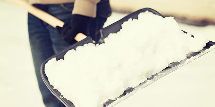 Man Holding Shovel Filled With Snow