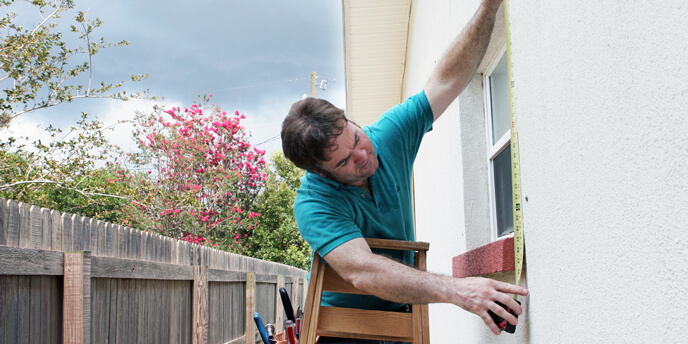Image of a Man Measuring Windows for Storm Shutters