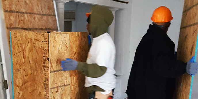 Two Men Moving Plywood Panels