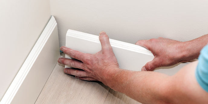 Man Fitting Baseboards Into Corner