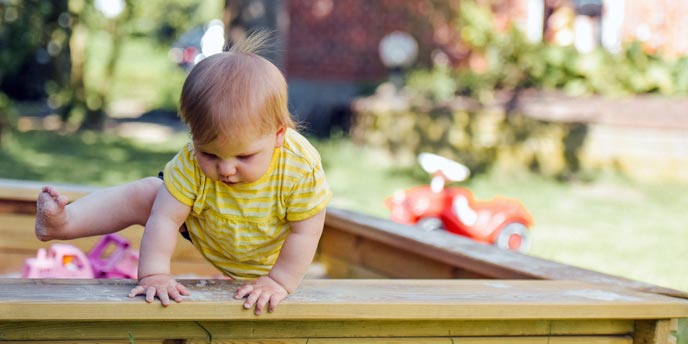 Young Baby Climbing Out of Sandbox