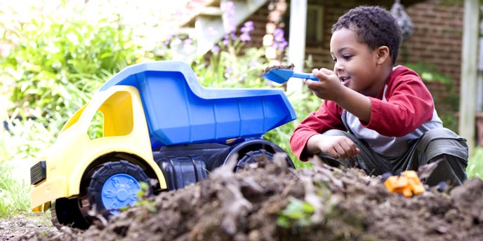Young Boy Playing With Dump Truck in Dirt