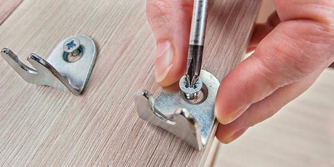 Man Unscrewing Fasteners From Couch Frame