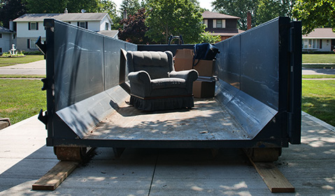 Loveseat Inside a Blue Roll Off Dumpster