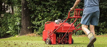Man Using Red Aerator on Lawn