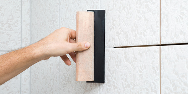 Man Applies Grout to Tile with Grout Float