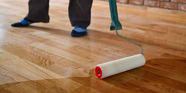 Foam Roller Applying Clear Finish Coat To Hardwood Floor