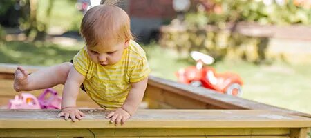 Young Baby Climbing Out of Sandbox