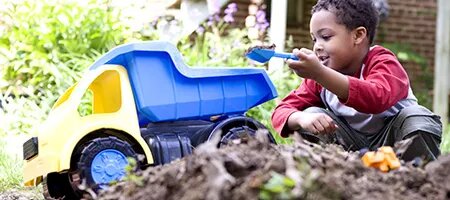 Young Boy Playing With Dump Truck in Dirt