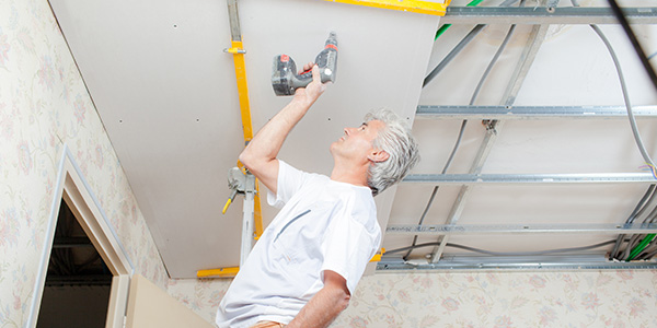 Person Installing Basement Ceiling Drywall