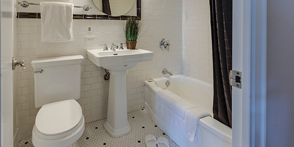 Bright Bathroom With Pedestal Sink and Round Mirror