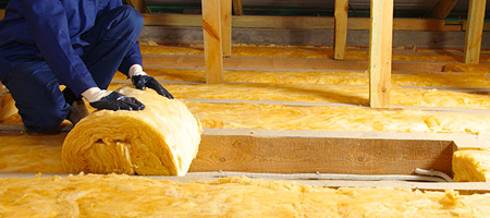 Person Unrolling Insulation Between Attic Joists.