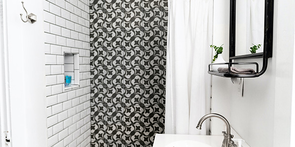 Black and White Tiled Shower Next to Vanity in Small Bathroom