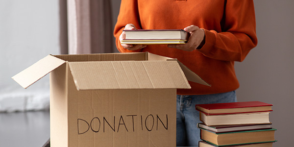 Person Placing Books in Donation Box.