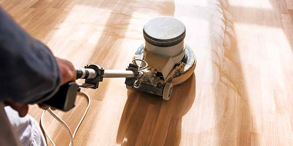 Man Using Buffing Machine On Hardwood Floor