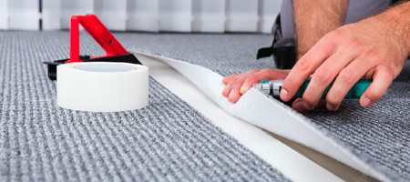 Homeowner With Tools Installing Strips of Carpet