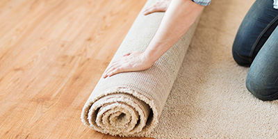 Person Rolling Up Beige Carpet