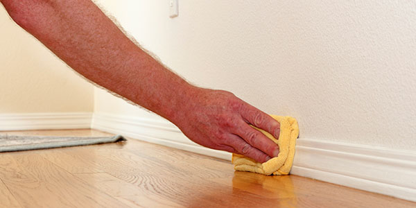 Man Wiping Down Baseboard With Cloth
