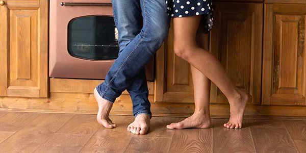 Legs of Barefoot Couple Standing in Kitchen With Hardwood Floor