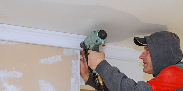 Man Installing Crown Molding With Nail Gun