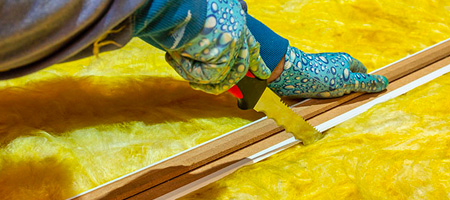 Person Cutting Insulation With Straightedge and Insulation Knife.