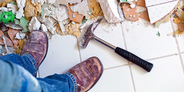 Man Wearing Boots With Hammer on Demolished Tile Floor
