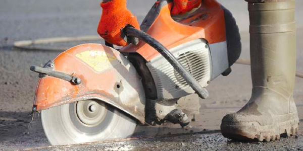 Man Cutting Asphalt With Circular Saw