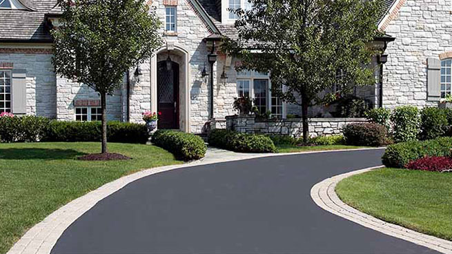 Gray Stone House With Curved Driveway and Green Lawn