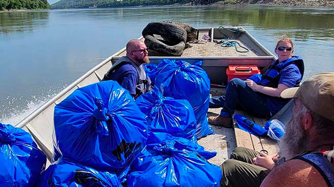 Volunteers in Boat With Blue Trash Bags