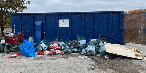 Blue Dumpster With Bags of Trash