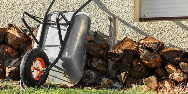 Firewood Stacked Next to House With Wheelbarrow