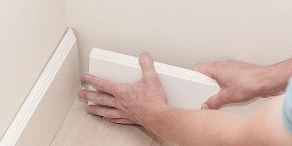 Man Fitting Baseboards Into Corner