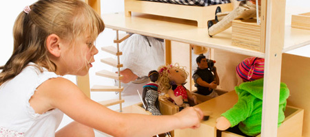 Young Girl Playing with Dolls In Wooden Doll House