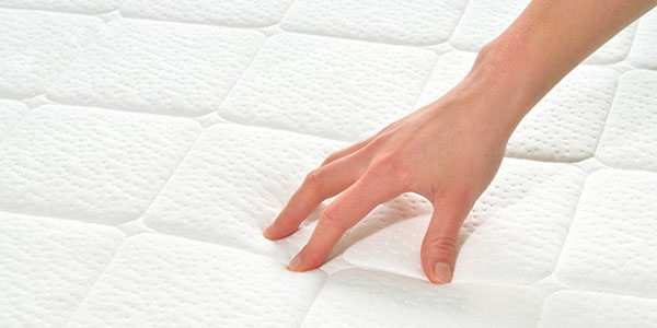 Person's Hand Testing Mattress Firmness