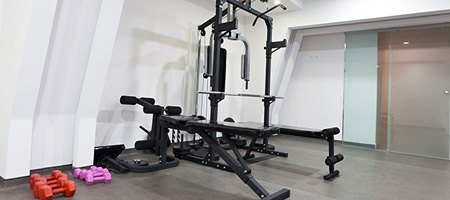 Weight Benches and Lifting Machines Near Dumbbells in Basement Home Gym