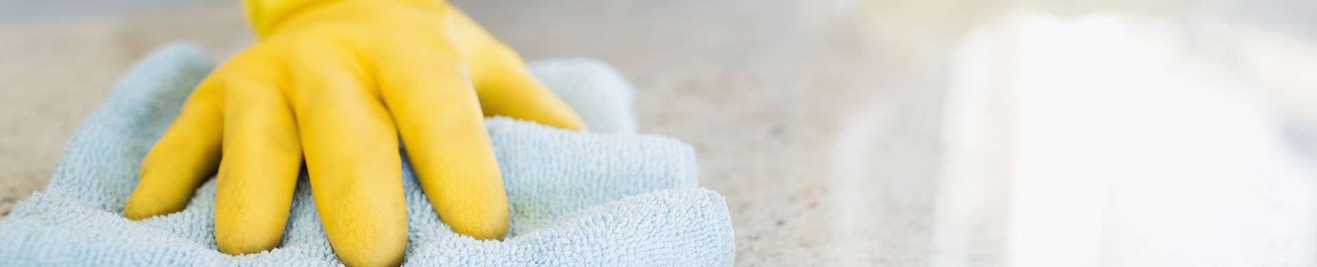 Homeowner Cleans Countertop With Rag and Yellow Gloves