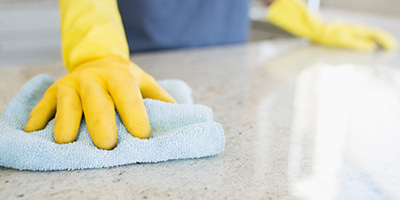 Homeowner Wearing Yellow Gloves Wiping Countertop With Rag