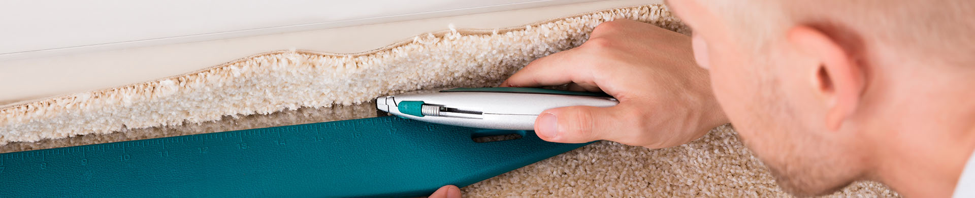 Man Cutting Carpet With Utility Knife