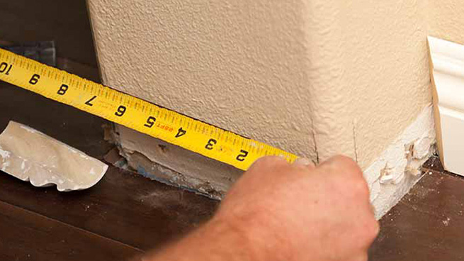 Man Measuring Wall With Tape Measure