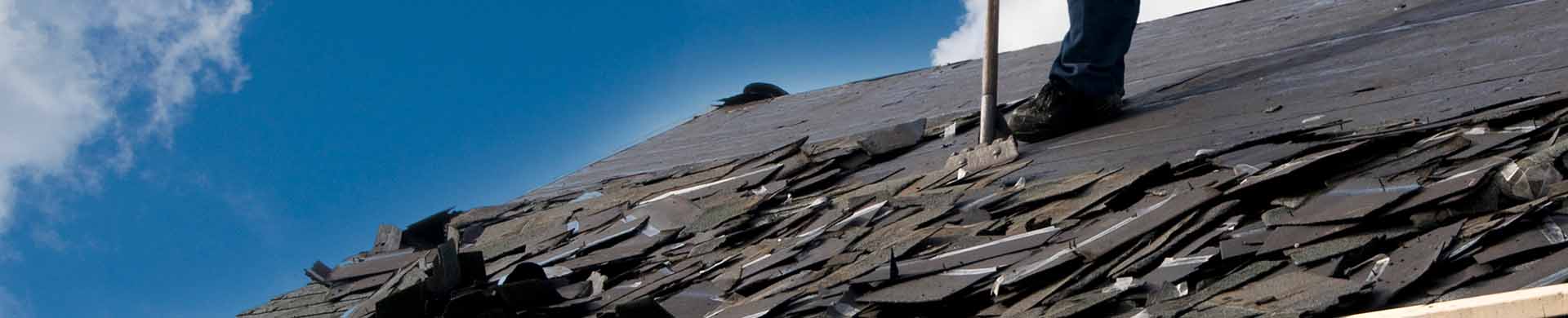 Worker Removing Shingles From Roof