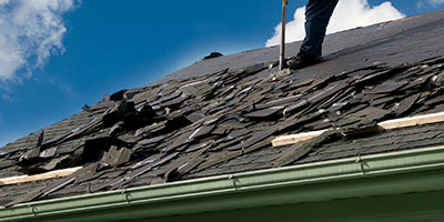 Worker Removing Shingles From Roof